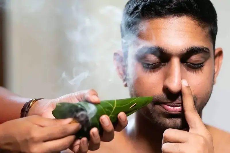 A practitioner guiding a traditional herbal smoke inhalation treatment