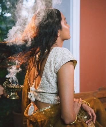 Herbal smoke rising through a woman's hair during a hair fumigation ritual