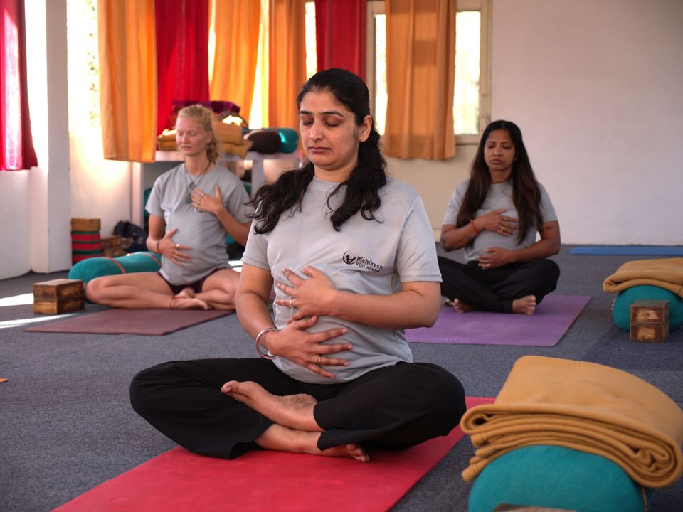 Expectant mothers practising gentle seated breathing exercises on yoga mats