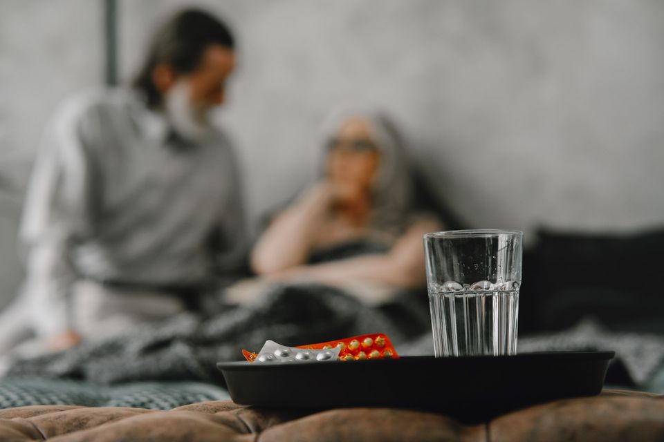 Medicines and a glass of water arranged on a tray for a resting patient